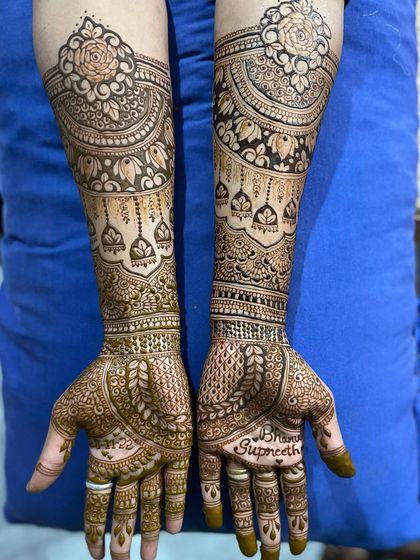 A gorgeous full bridal design with a mix of leafy patterns on the fingers and intricate bands on the arms. The bride's and groom's names are beautifully written on the palms.