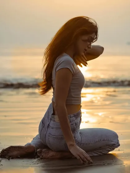 A contemplative pose on the beach, with the golden light of the sunset creating a warm and serene atmosphere.