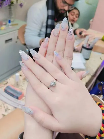 An elegant and icy look created with long, tapered nail extensions and a dense silver glitter gradient. This is a perfect example of a sophisticated party or wedding nail design.