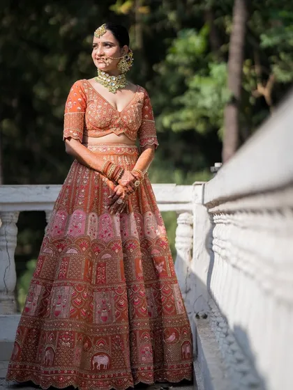 A full-length view of the bride on a balcony, surrounded by greenery. The natural light makes her skin look incredibly fresh and dewy.