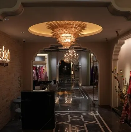The arched entryway into the Eclat boutique, designed to feel like a passage into a world of luxury. A stunning gold-leafed chandelier and patterned marble flooring set a tone of opulence from the very first step.