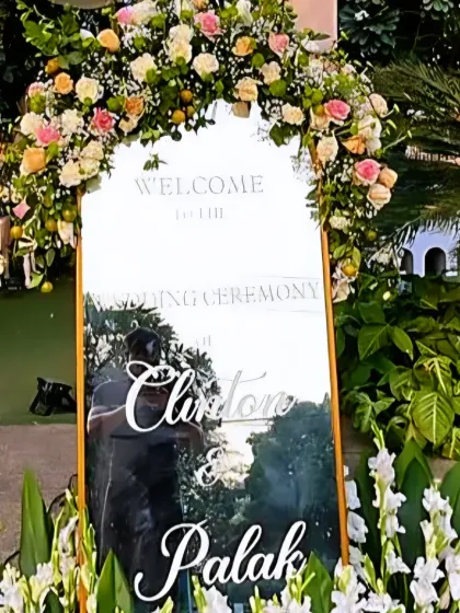 The personalized welcome sign for Clinton and Palak's wedding, framed by a beautiful arch of pastel roses.