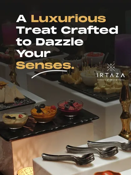 A luxurious appetizer spread featuring various dips like hummus, along with cheese and olives. The presentation on multi-level black slate platters, accented by golden candelabras, adds a touch of modern elegance.