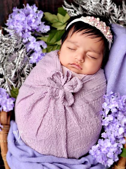 A close-up of the baby in the rattan chair, surrounded by a halo of purple flowers.