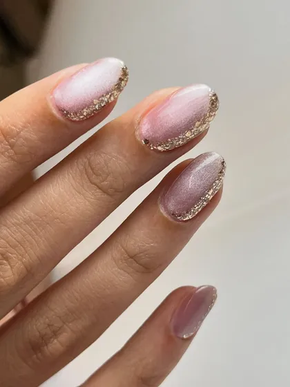 A detail shot of the gold glitter cuticle accent on the soft pink cat-eye base.