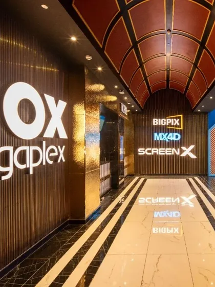 The entrance to the premium format theaters at INOX Jalosa, including BigPix, MX4D, and ScreenX. The design uses a rich palette of gold and dark wood, with bold branding and reflective surfaces to signify a heightened, state-of-the-art cinematic experience.