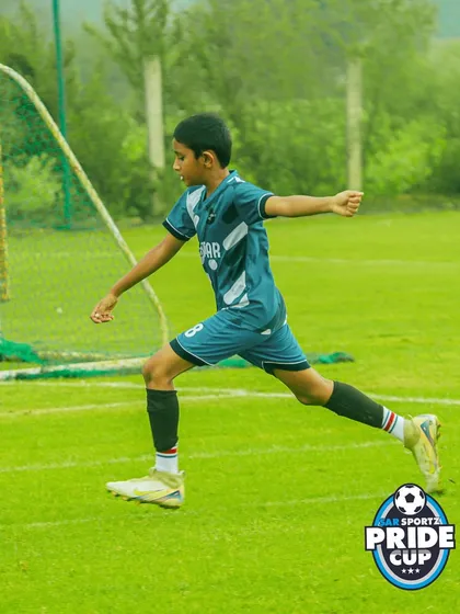 A young athlete follows through on a powerful shot towards the goal, demonstrating excellent form and balance during a competitive match.