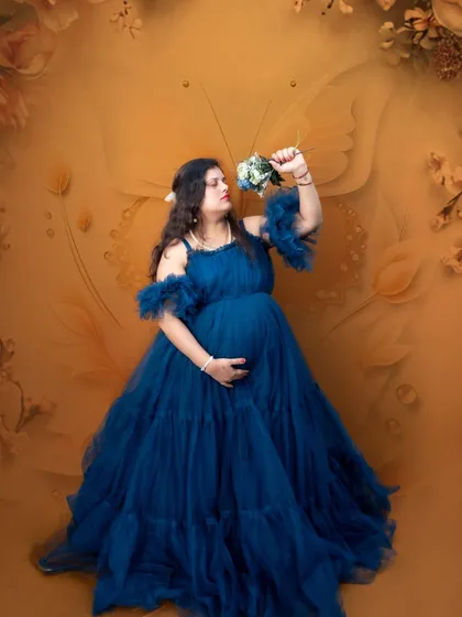 A thoughtful moment captured in the studio. The deep blue gown looks stunning against the warm, golden backdrop embossed with butterfly motifs.