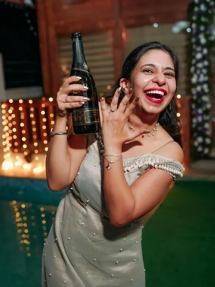 Popping the champagne to celebrate! A candid shot of the bride's exuberant happiness during the engagement party.