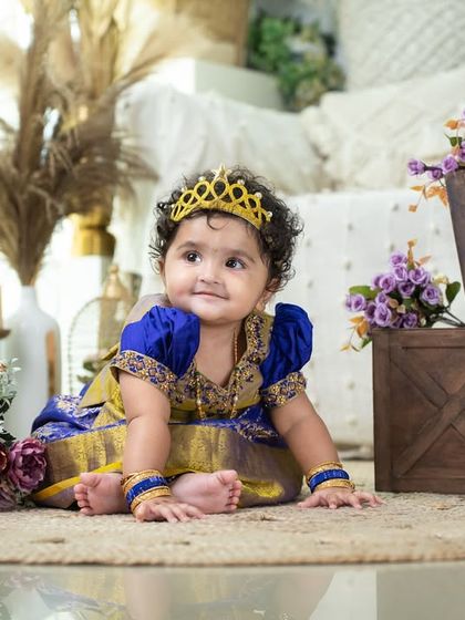 A little princess in a traditional blue and gold 'pattu pavadai'. The crown and floral setting make her look like true royalty.