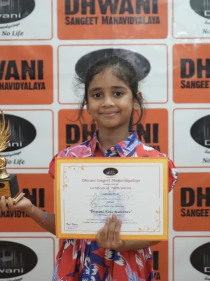 A young student proudly holds her certificate and trophy.