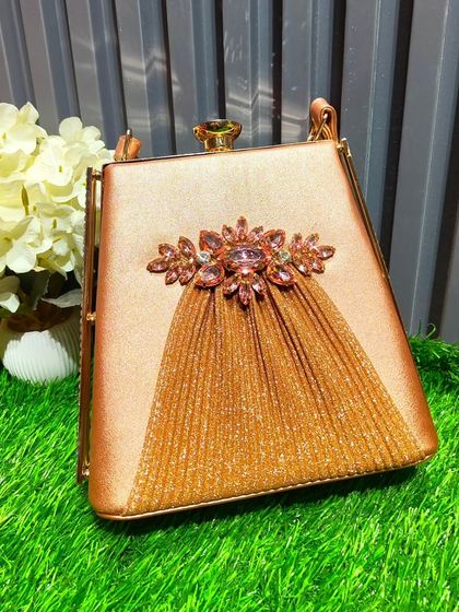 This gold satin clutch features a beautiful crystal and tassel embellishment, making it a luxurious accessory for a bride or a wedding guest.