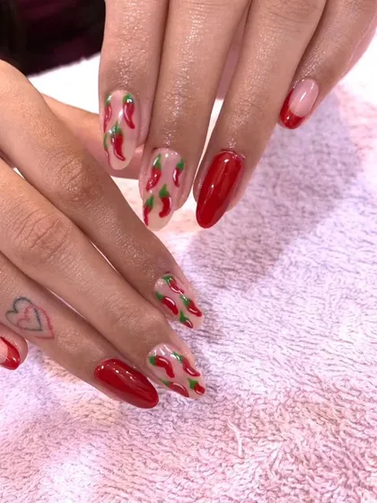A fun and spicy set of red nails with accent nails featuring hand-painted red hot chili peppers.