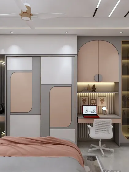 A close-up of the study and wardrobe area in a kids' room. The design is compact, functional, and uses a modern color palette of pink, grey, and white.