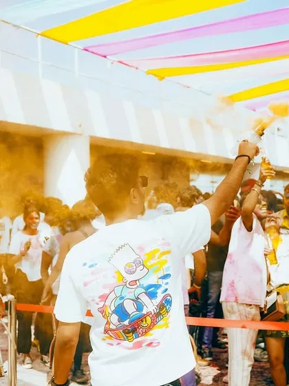 The view from the stage at the Holi 2k25 festival. A sea of people, vibrant colors, and a dhol player getting the crowd hyped.