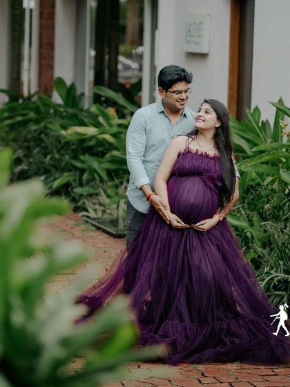 A beautiful couple's maternity portrait in a garden. The deep purple tulle gown is a romantic and elegant choice for expecting parents.