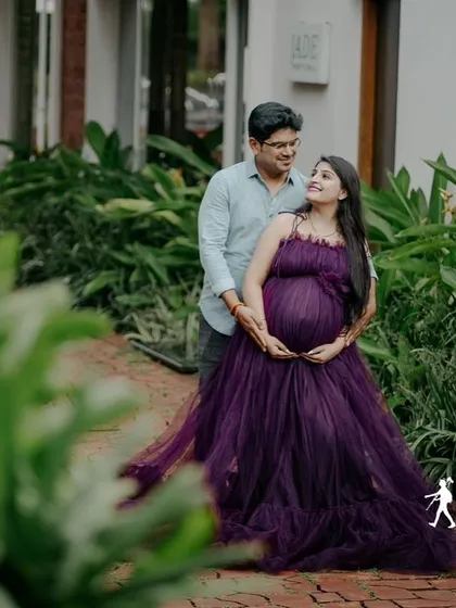 A beautiful couple's maternity portrait in a garden. The deep purple tulle gown is a romantic and elegant choice for expecting parents.