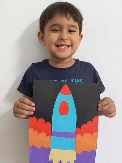 "To the moon!" A student proudly displays his awesome paper rocket ship craft, complete with fiery exhaust.