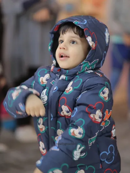 A young boy, bundled up but full of expression, participates in an outdoor drama game.