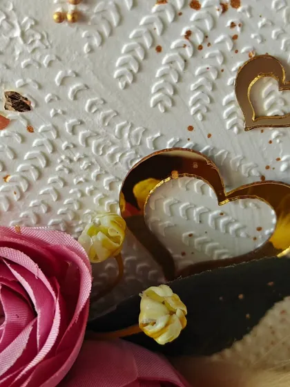 A detailed shot of the top-forward anniversary cake, showing the texture from the stencil and the delicate golden heart accents.