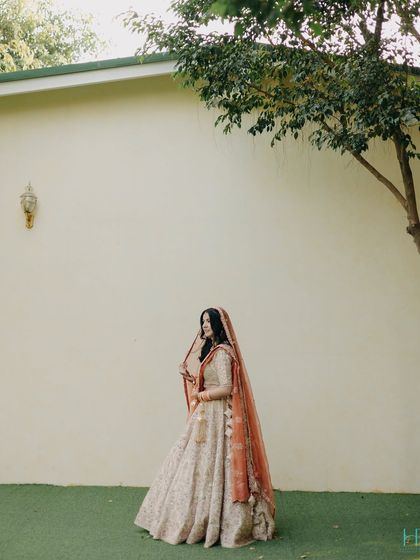 A minimalist bridal portrait, with the bride standing against a simple wall, her elegant silhouette framed by a tree.