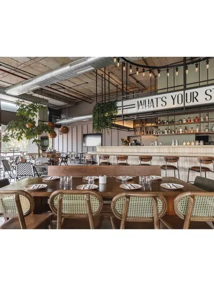 This wide shot demonstrates the scale of the space and the effectiveness of the open-plan design. The bar remains the central focus, visible from almost every point in the restaurant.