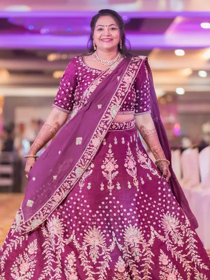 The mother of the groom looking regal in her purple lehenga. The makeup is elegant and refined, perfect for her important role.