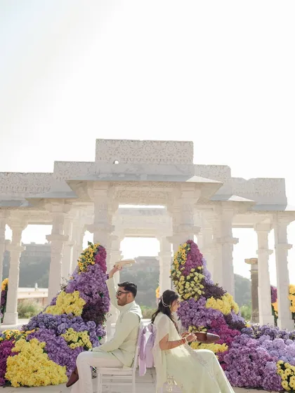 A playful moment during the Haldi ceremony, where the bride applies haldi to the groom against the backdrop of the stunning floral installation.