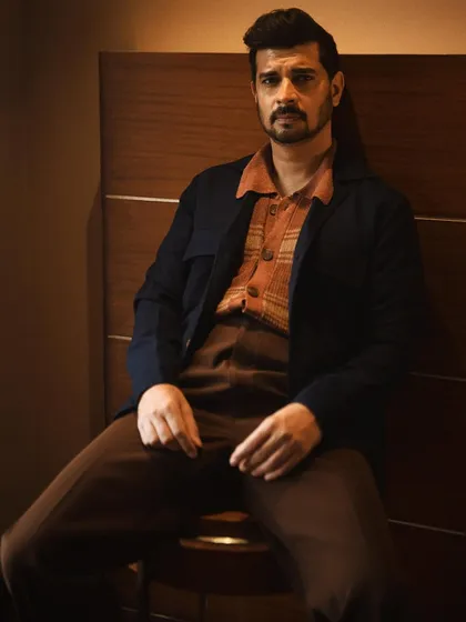 Tahir Raj Bhasin in a relaxed, seated pose. The play of shadow and light across his face adds depth and character to this portrait.