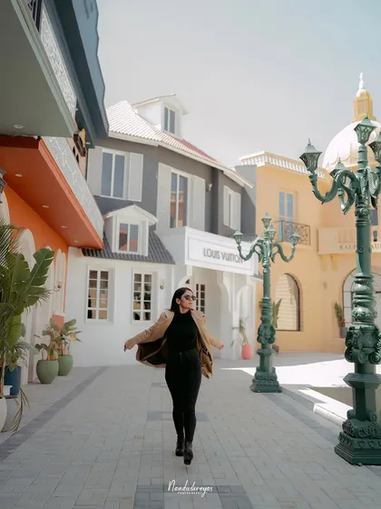 A solo shot of the bride-to-be walking confidently down a stylized urban street, her coat flowing behind her.