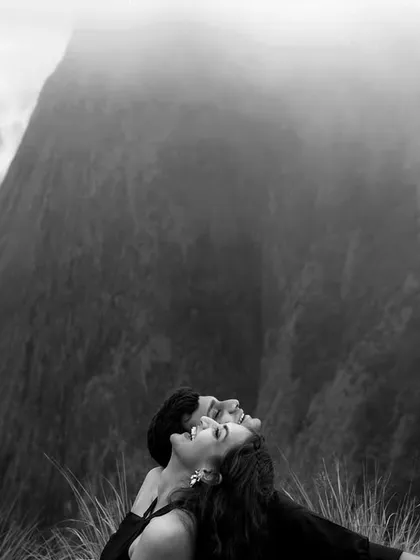 A dramatic black and white shot with the couple looking up towards the sky, framed by the majestic, misty mountains of Munnar. This composition creates a sense of awe and shared dreams.