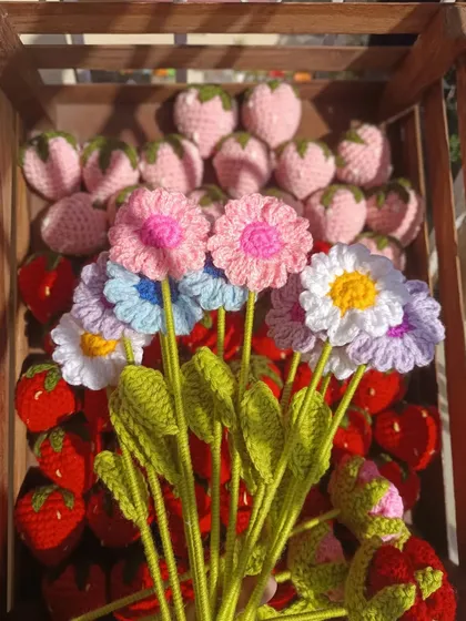 A small bouquet of mixed daisies against a background of strawberries.