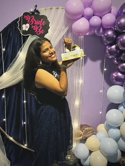 The bride-to-be holding up her cake in front of the beautiful balloon arch. This is a perfect spot for taking photos before everyone digs in.