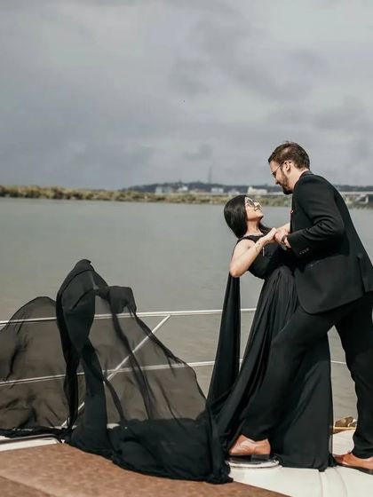 A playful and romantic moment captured on the yacht. The flowing black trail gown adds a sense of movement and fun to the pre-wedding photos.