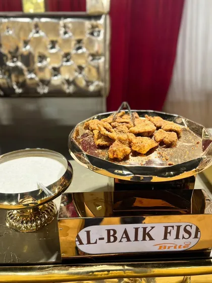 A platter of Al-Baik style fried fish, served with a creamy dipping sauce, offering a unique international flavor.