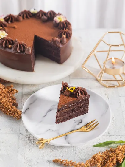 A slice of our rich chocolate cake, served on a marble plate. It's a perfect dessert for any party or gathering.