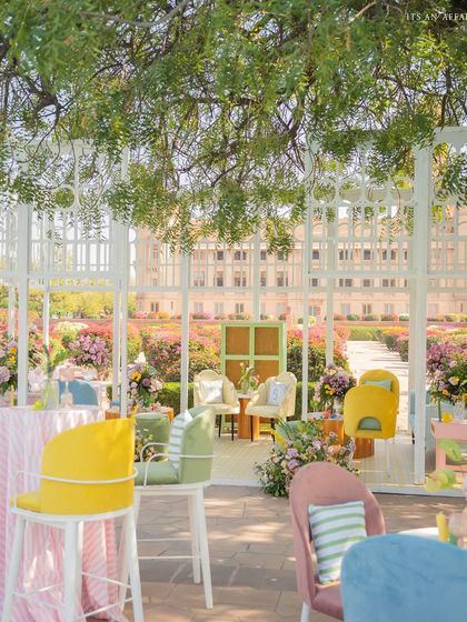 A view from under a shady tree, looking out at the colorful seating areas and the magnificent palace in the distance.