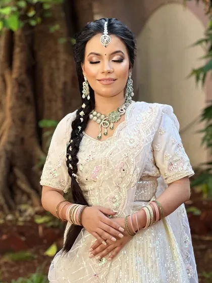 A serene bride in an all-white ensemble, perfect for a daytime wedding or Nikah ceremony. The pastel green stone jewellery adds a soft touch of color.