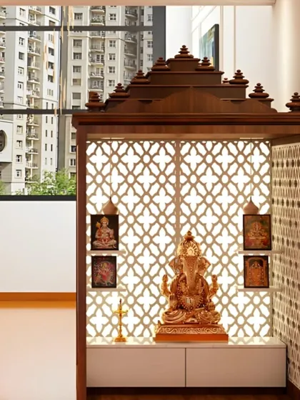 This design shows how we create a beautiful pooja corner in an apartment with a view. The wooden mandir features a traditional temple-style roof and an intricate jaali screen as a backdrop, which is backlit to create a warm, inviting glow. It’s a self-contained unit that feels both grand and perfectly suited for a modern living space.