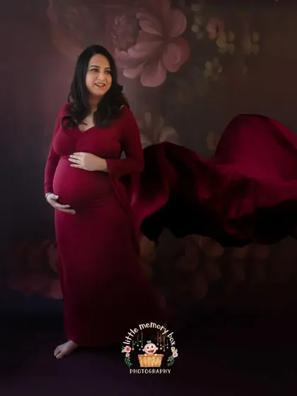 This portrait combines a rich, dark floral backdrop with a flowing red gown for a truly artistic and romantic feel. The fabric toss adds a sense of movement and grace.