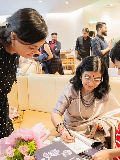 A young boy looks on with curiosity as Dr. Kavita Pania signs a book for his family, a moment that might inspire a future writer.