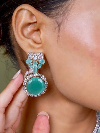 A close-up of the earrings from our mint green American diamond set. The circular design with a halo of smaller stones is both modern and timeless.