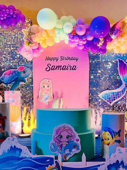 An underwater fantasy with this Mermaid theme decoration, featuring characters from The Little Mermaid, a sequin backdrop, and a colorful balloon arch.