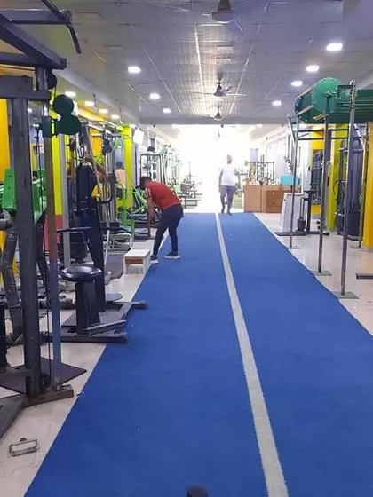 A full view of our training floor. You can see the long turf track for sprints and sled work, with various strength stations and free weight areas alongside it. There is space for everyone to focus on their workout.