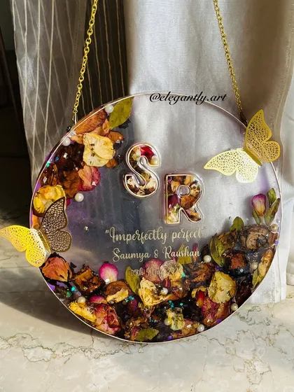 This unique transparent frame preserves flowers in a floating style, complete with the couple's initials and delicate butterfly accents. It gives the illusion of flowers encased in glass.