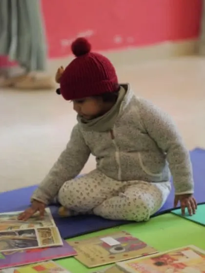A young child explores picture books on his own terms, an important part of developing a love for stories.
