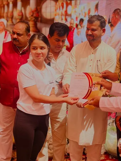 A student receiving her certificate and award at a yoga event, her smile says it all.