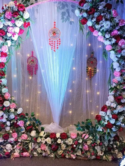 A view of the Bohemian-style floral ring backdrop without the seating. This shows the full structure, including the sheer white drape and fairy lights that create a magical effect.