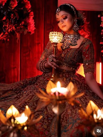 A stunning, candle-lit shot of a bride in a deep red embroidered lehenga, creating a very romantic and regal atmosphere.