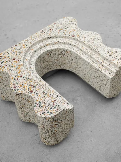 Close-up details of the custom terrazzo bookshelf, highlighting the smooth curves and the beautiful texture of the multi-colored stone chips.